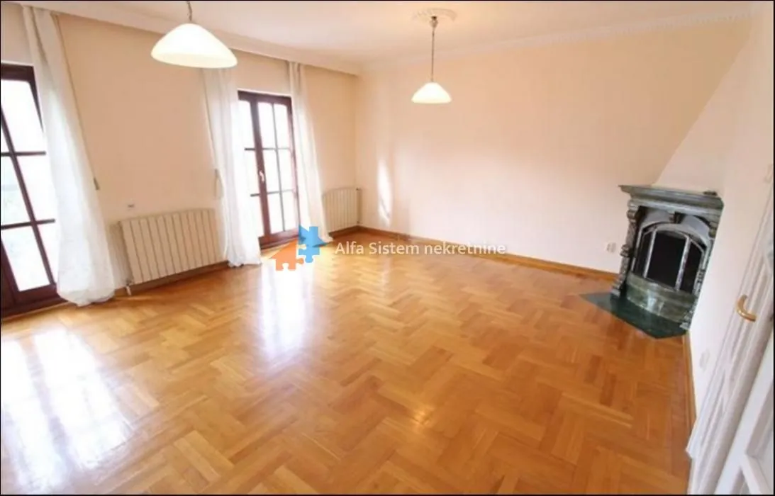 Empty living room with fireplace, parquet flooring and balcony doors.
