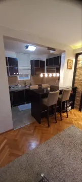 Kuhinja sa tamnim elementima i šankom sa barskim stolicama. - image 5