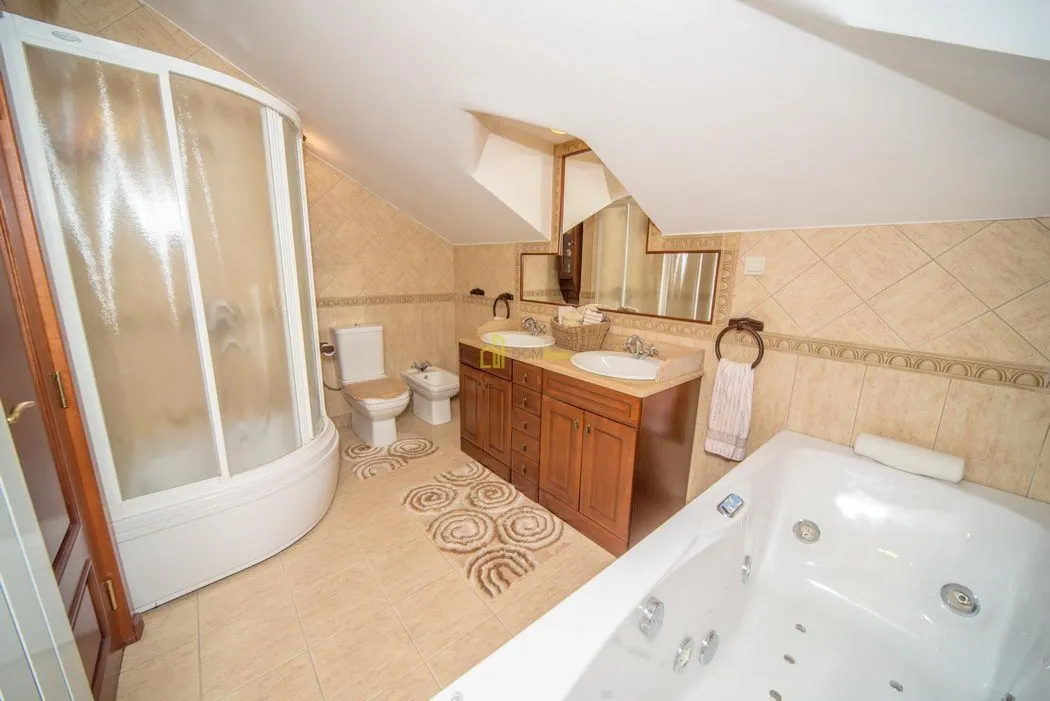 Bathroom with a shower cabin, hydromassage bathtub, and wooden vanity.