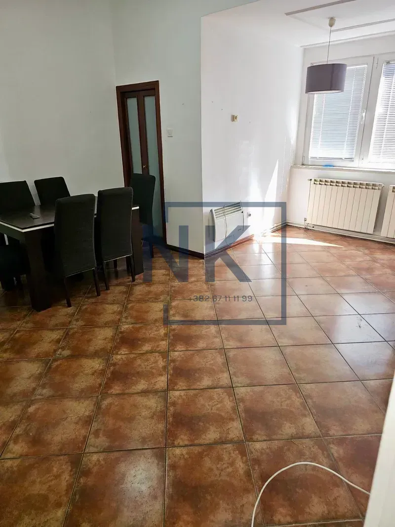 Dnevna soba sa trpezarijskim stolom i stolicama, podom obloženim pločicama i prozorom.