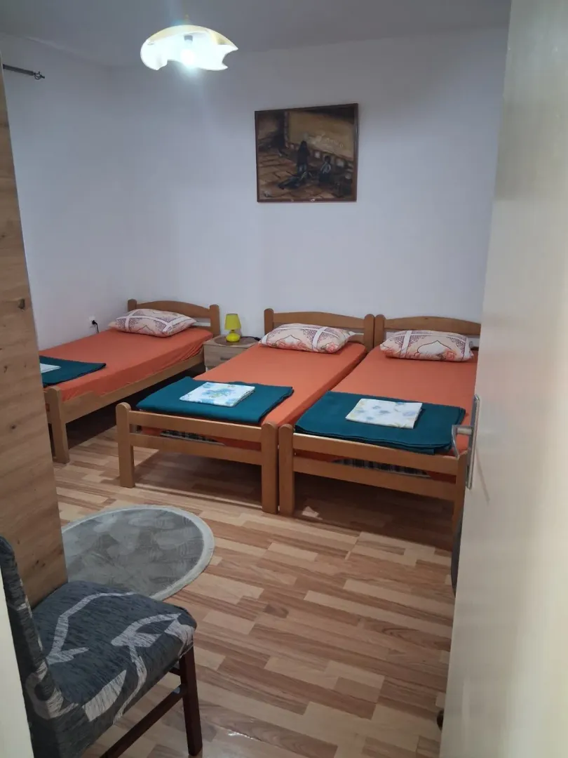 Spavaća soba sa tri drvena kreveta i laminatom na podu.