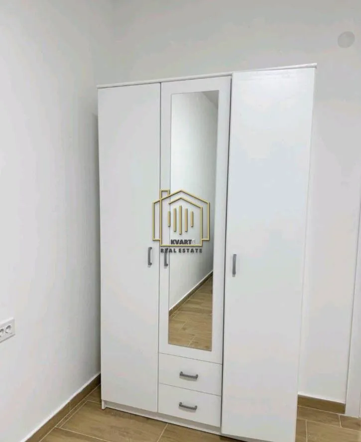 Bijeli garderober sa ogledalom i dvije ladice u sobi.