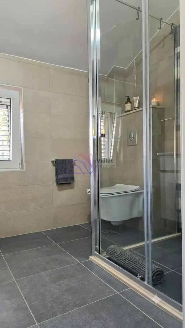 Modernly equipped bathroom with a shower cabin and a wall-mounted toilet.