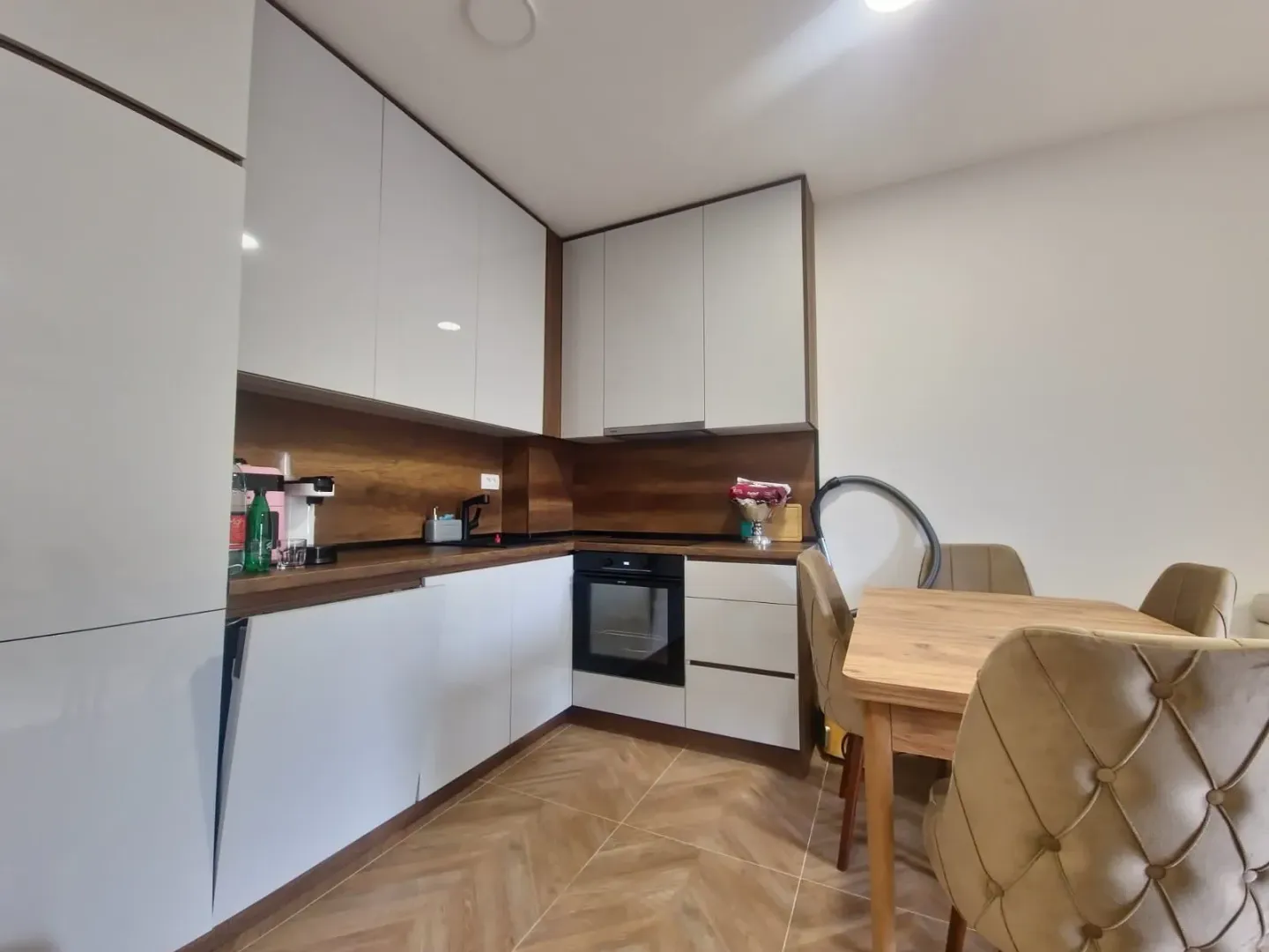 Modern kitchen with white units and a dining table.