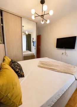 Furnished bedroom with a double bed, mirrored wardrobe, and a wall-mounted TV. - image 3