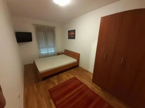 Jednostavna spavaća soba sa drvenim krevetom i ormarom. - image 4
