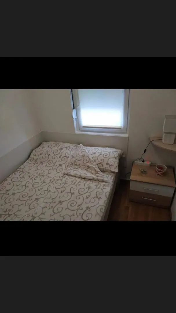 Manja spavaća soba sa krevetom i noćnim stočićem.