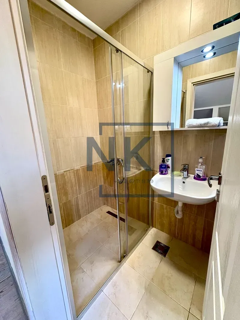 Bathroom with a walk-in shower, washbasin, and a mirrored cabinet.