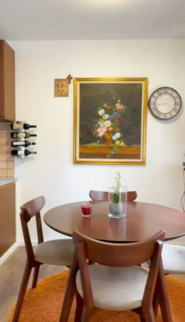 Dining area with a round wooden table, chairs, and decorative wall elements.