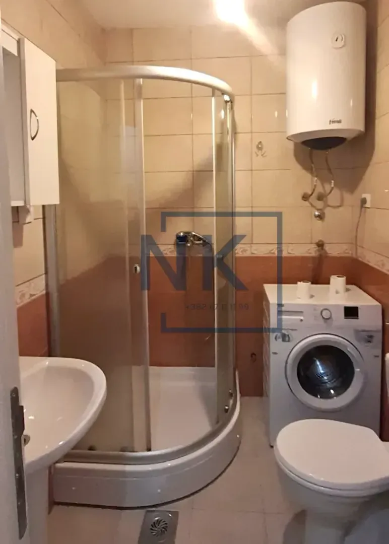 Manje kupatilo sa tuš kabinom, umivaonikom, veš mašinom i bojlerom.