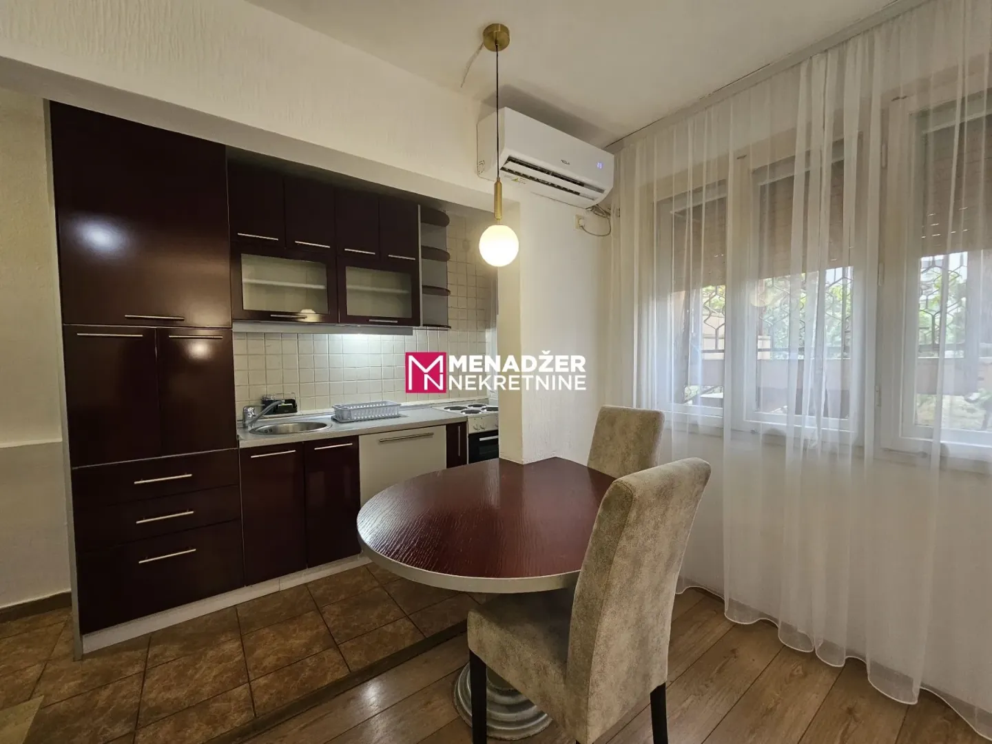 Kitchen with dark cabinetry and a dining table with chairs by the window.