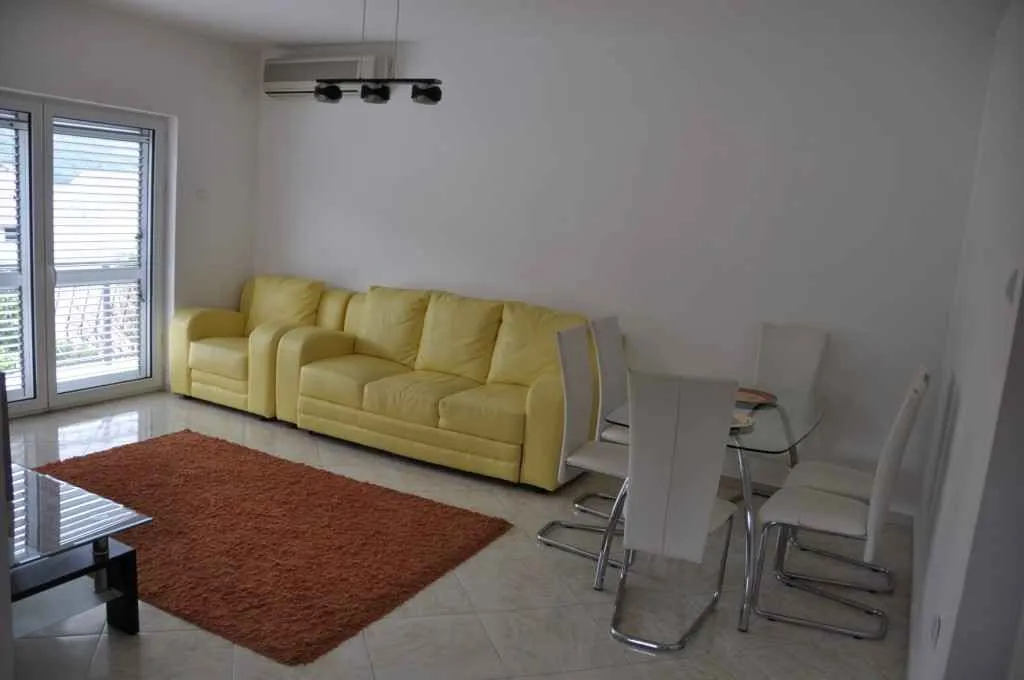Svijetao dnevni boravak sa žutom kožnom garniturom i trpezarijskim stolom.