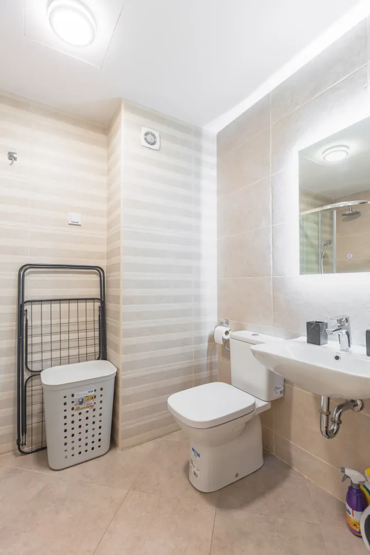 Moderne kupatilo sa umivaonikom, WC šoljom i korpom za veš.