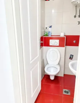 Small bathroom with white and red tiles and a toilet. - image 4