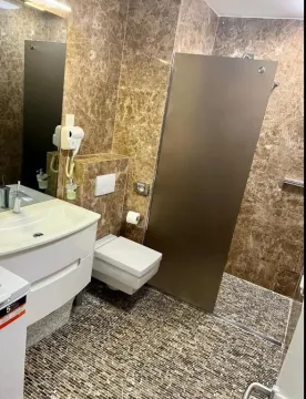 Modern bathroom lined with marble tiles featuring a walk-in shower. - image 19