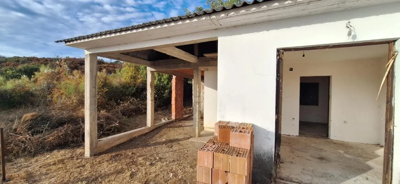Spoljašnji izgled kuće u izgradnji sa natkrivenom terasom i dvorištem.