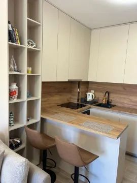Small kitchen with a breakfast bar, beige cabinets, and wood-grain details. - image 11