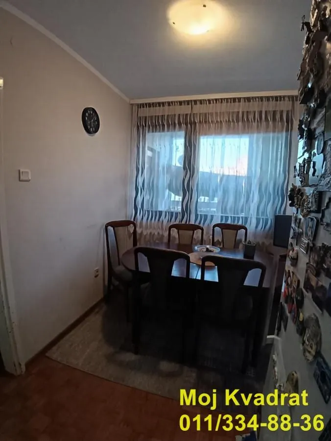 Trpezarija sa stolom i stolicama pored prozora.