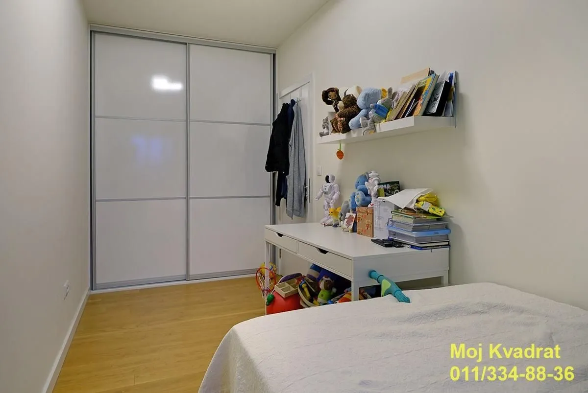 Children's bedroom with a large built-in wardrobe, desk, and bed.