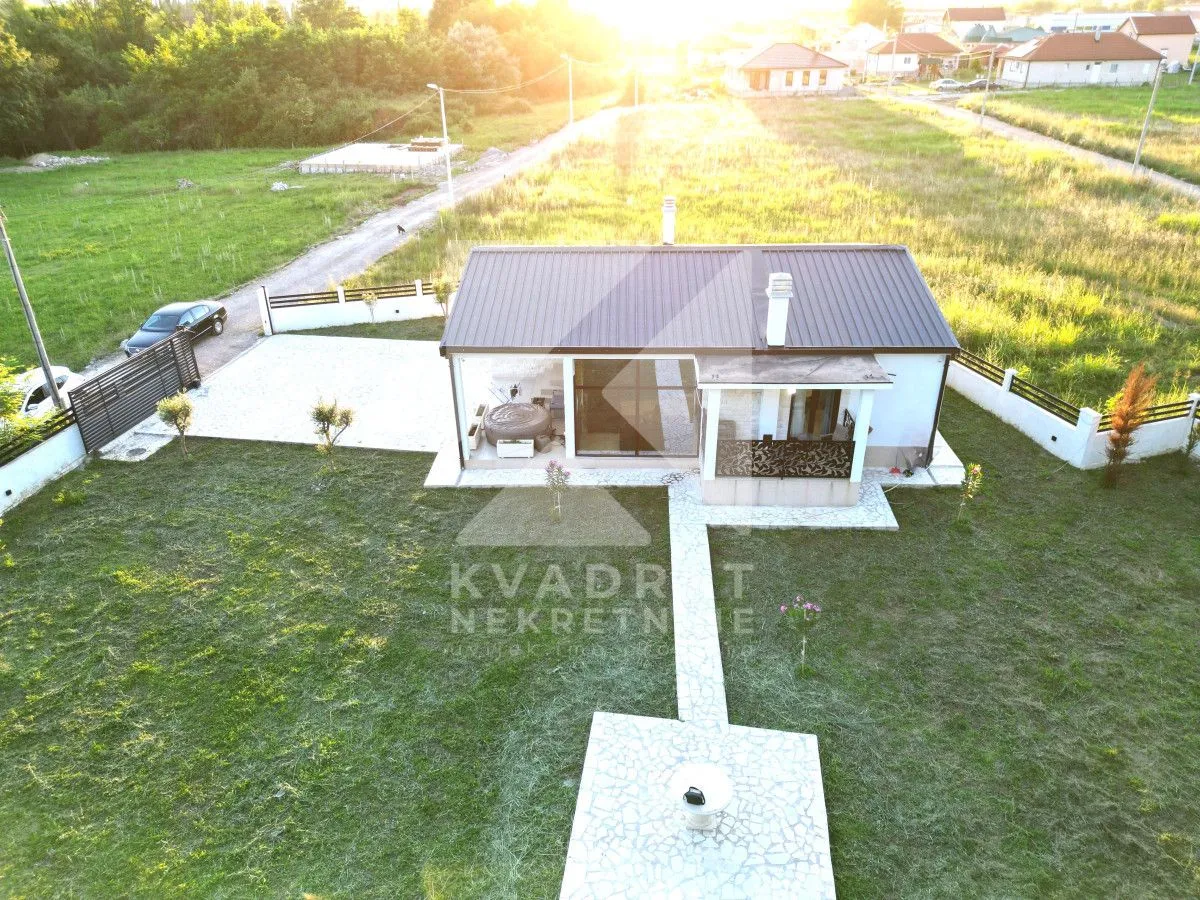 Aerial view of a single-story house with a landscaped yard and lawn.