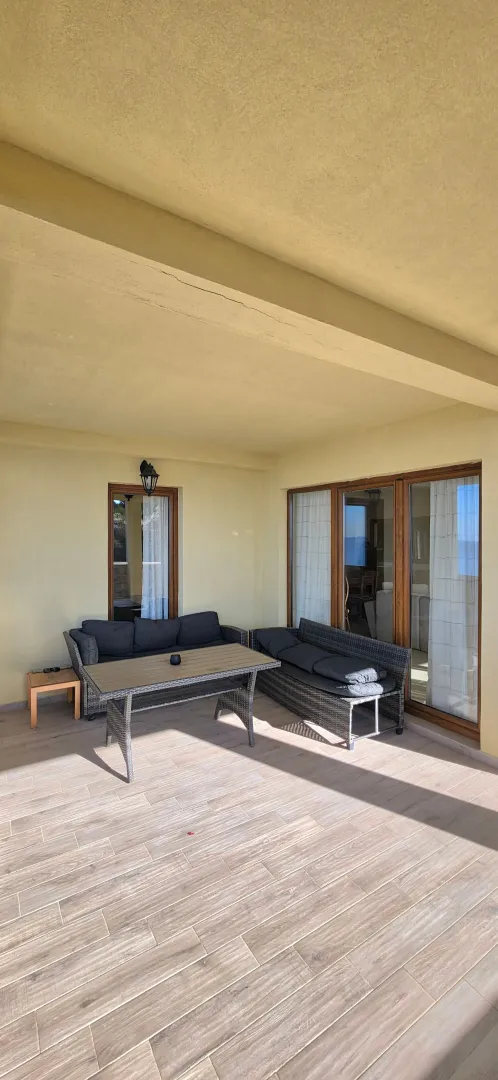 Covered terrace with outdoor seating furniture and a view.