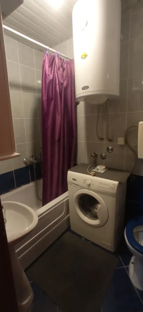 A simple bathroom with a bathtub, washing machine, and water heater.