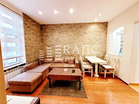 Living room with a sofa, dining table, and decorative stone wall. - image 11
