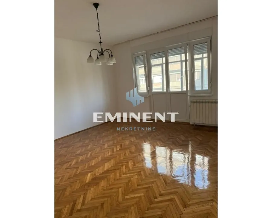 Empty room with parquet flooring and balcony doors.