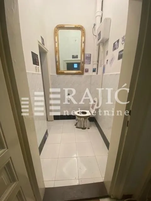 View of the bathroom with toilet, mirror, and tiling.