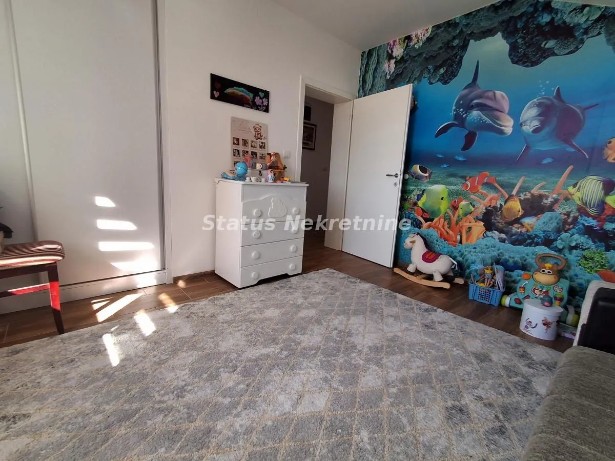 Dečja soba sa zidnim tapetom sa motivom podmorja, komodom i igračkama.