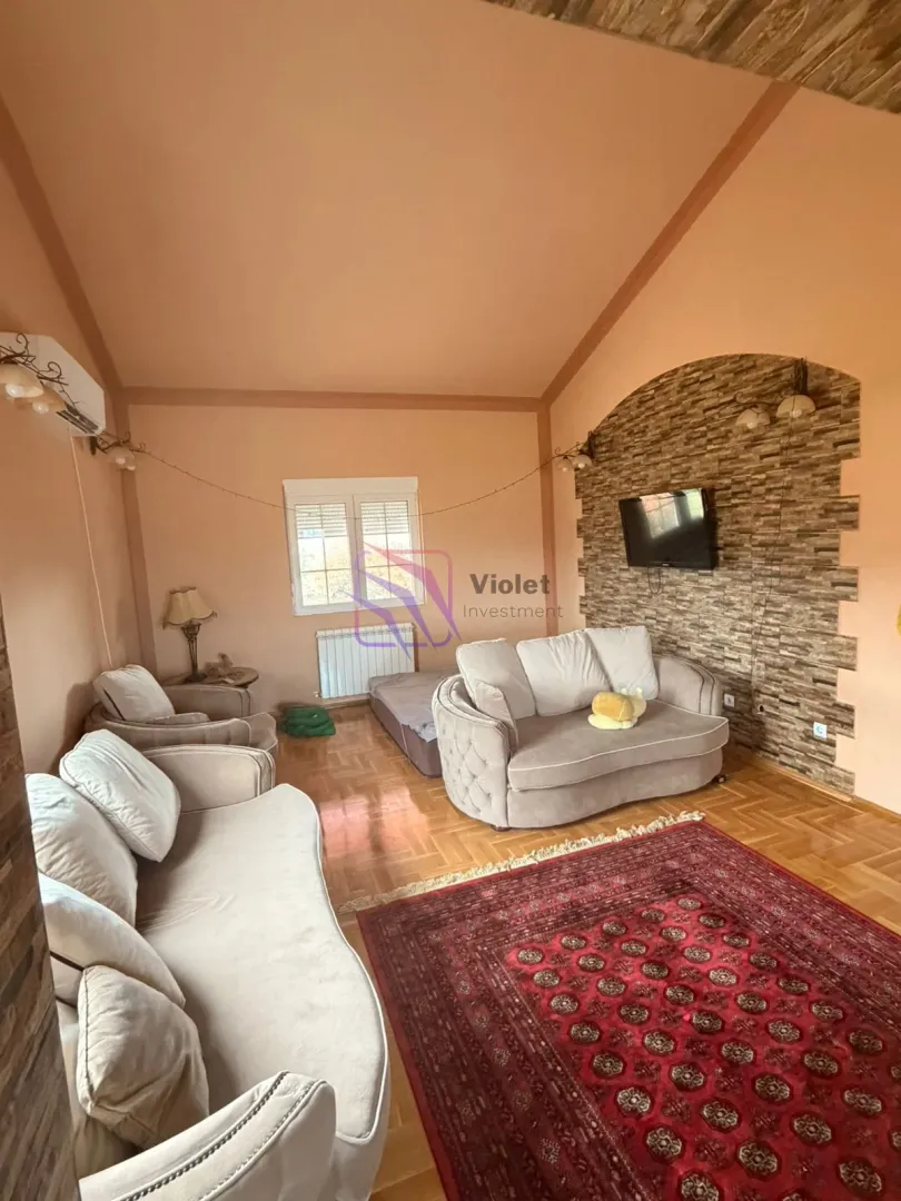 Living room with seating furniture, TV, and a decorative stone wall.