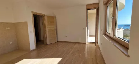Prazna prostorija sa drvenim podom, vratima i pogledom na more kroz prozor. - image 8