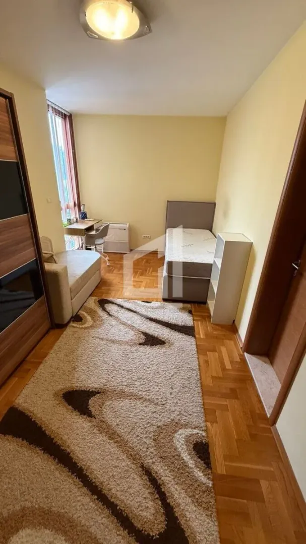 Furnished bedroom with a bed, wardrobe, and desk.