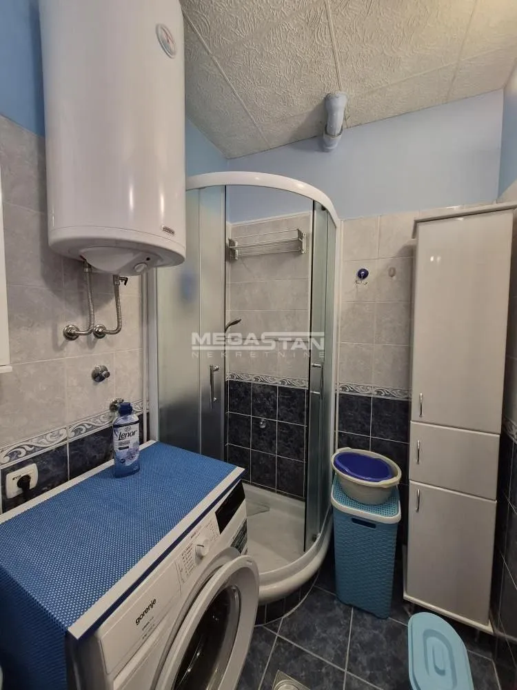 Bathroom equipped with a shower cabin, washing machine, water heater and storage cabinet.