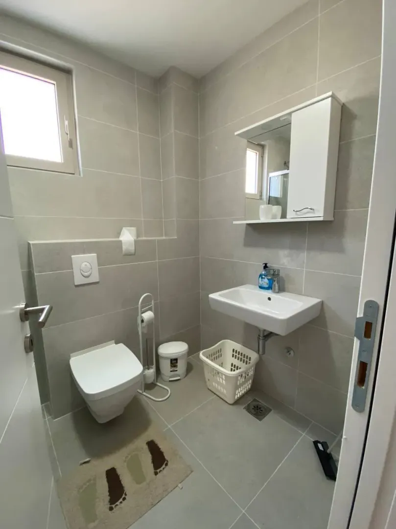 Small bathroom with grey tiles, toilet, and sink.