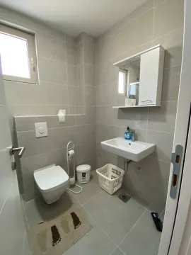 Small bathroom with grey tiles, toilet, and sink. - image 8