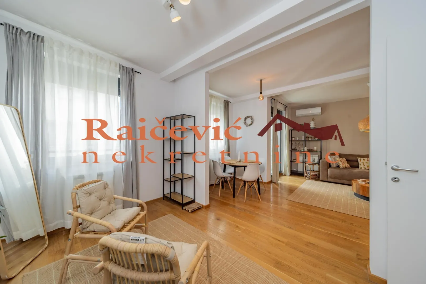 Spacious bright living room connected to the dining area with wooden flooring.