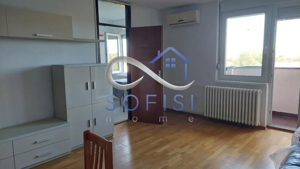 Dnevna soba sa drvenim podom, nameštajem i izlazom na terasu.