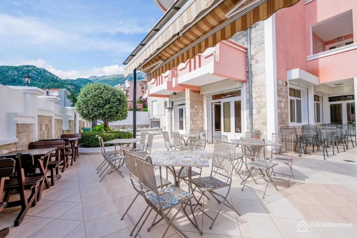 Spacious paved terrace with tables and chairs in front of the building.