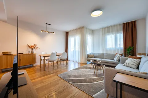 Spacious living room with sofa set, dining area, and wooden flooring. - image 2