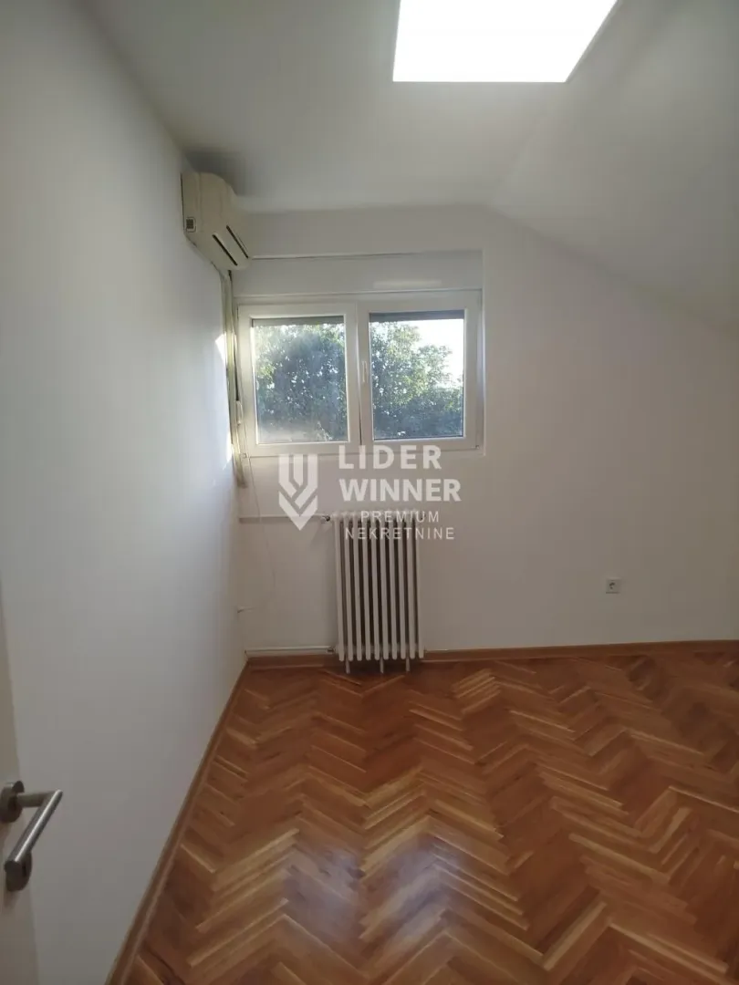 Empty room with parquet flooring and air conditioning.