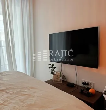 Pogled na dio spavaće sobe sa krevetom i televizorom na zidu. - image 7