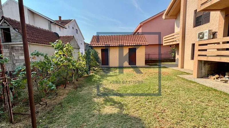 Dvorište sa travnjakom i pomoćnim objektom pored kuće.