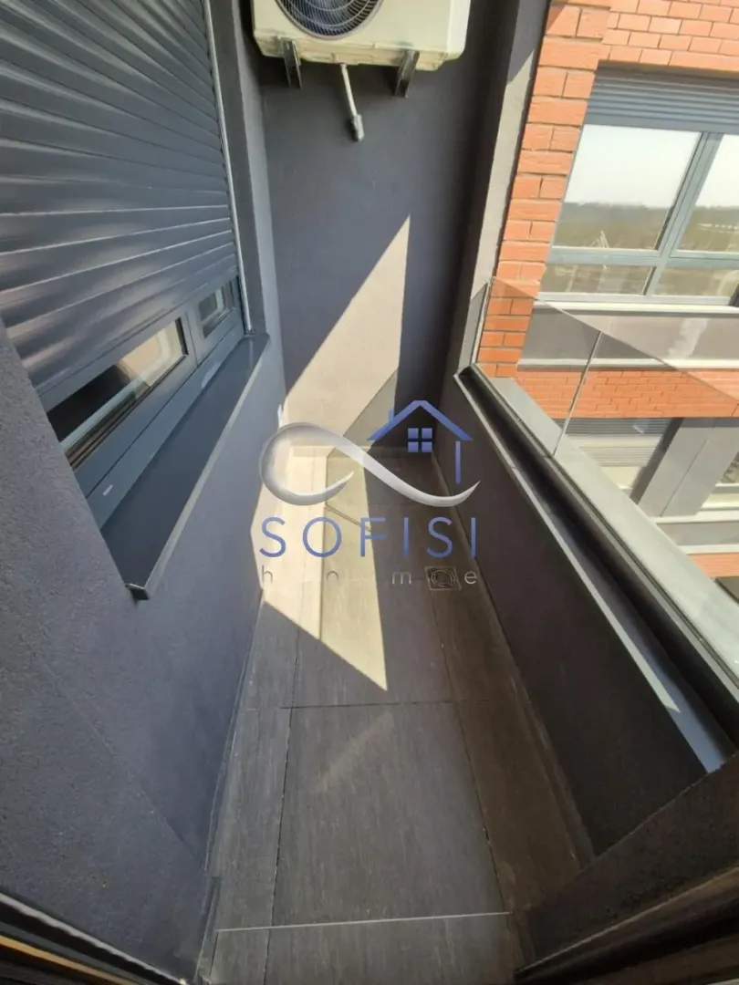 Manji natkriveni balkon sa keramičkim pločicama i staklenom ogradom.