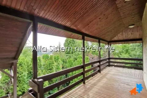 Covered wooden terrace overlooking green areas. - image 12