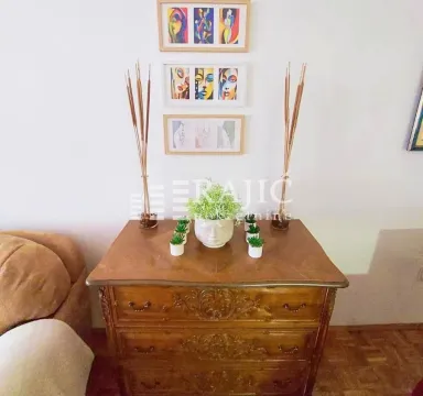 Interior detail featuring a wooden chest of drawers and decorative paintings on the wall. - image 4