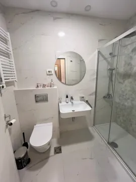 Modern bathroom tiled with marble-look tiles, featuring a walk-in shower and built-in fixtures. - image 7