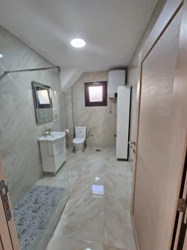 Bright bathroom with a shower area, sink, and toilet. - image 5