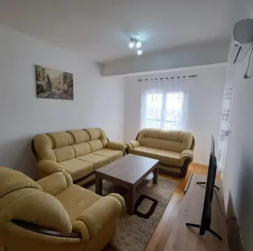 Svijetao dnevni boravak opremljen garniturom, stočićem i televizorom. - image 3