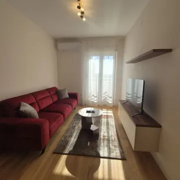Dnevna soba sa crvenom garniturom, stočićem i televizorom. - image 3